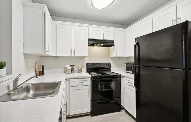 Model Kitchen with White Cabinets and Wood-Style Flooring at Huntington Place Apartments located in Sarasota, FL.
