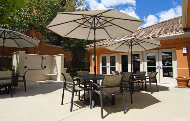 A patio with tables and chairs under umbrellas.