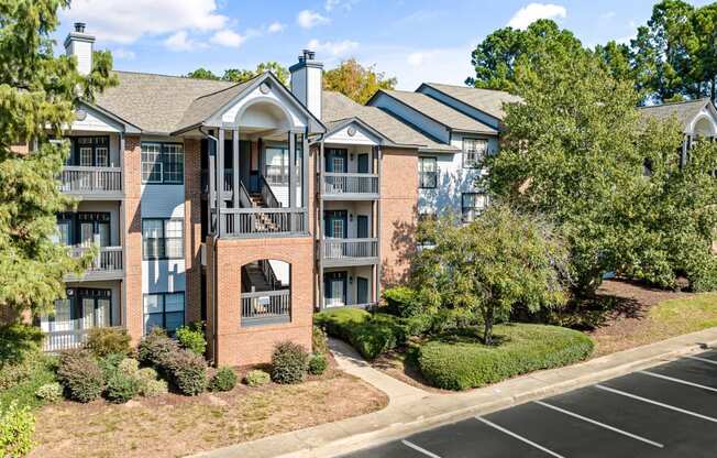 an apartment building with brick exterior and balconies with trees at View at Lake Lynn, Raleigh