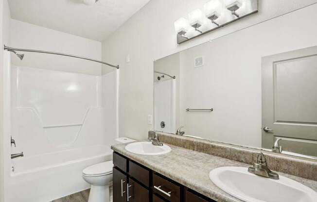A white bathroom with a toilet, sink, and shower.