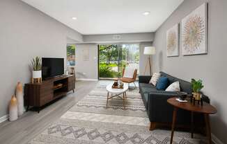 A living room with a grey couch, a wooden coffee table, and a television.