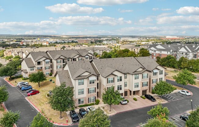 A large apartment complex with a parking lot in front.