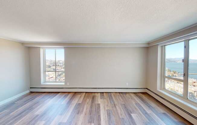 an empty living room with large windows and hardwood floors