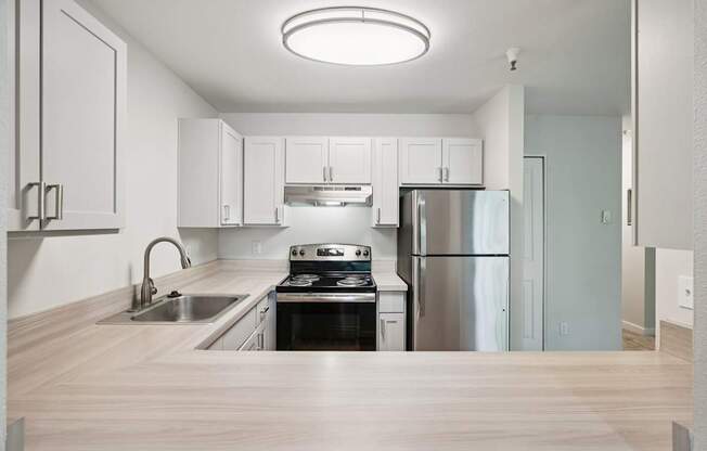 A modern kitchen with stainless steel appliances and wooden flooring.