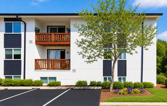 A white apartment building with a black parking lot in front.