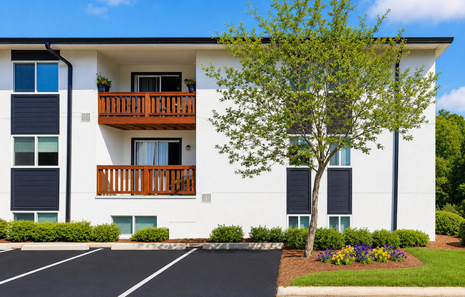 A white apartment building with a black parking lot in front.
