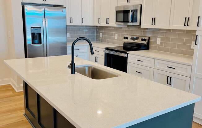 A kitchen with a white counter top and a black drawer.