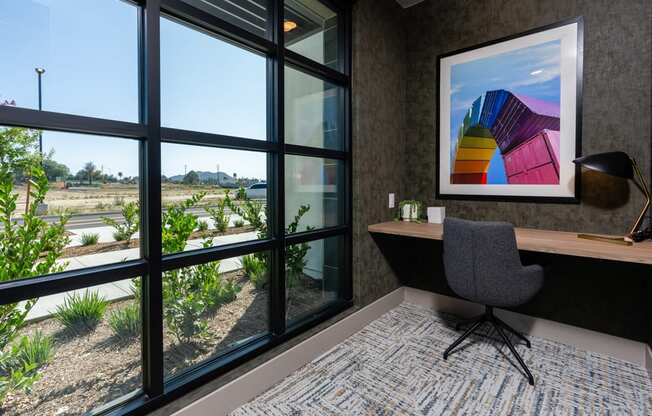 A room with a grey chair and a painting on the wall.