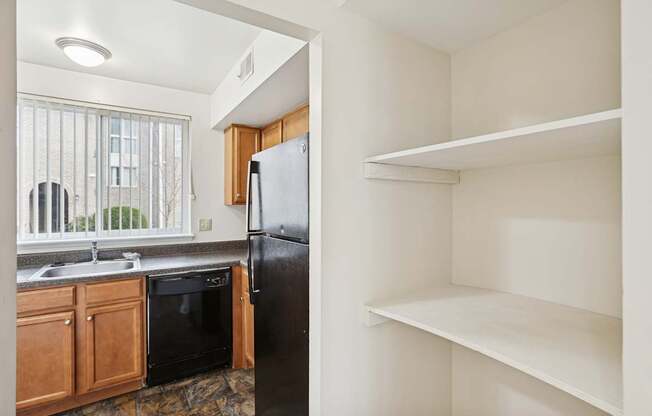 A kitchen with a black refrigerator and wooden cabinets.