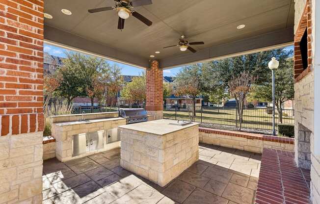 A patio with a ceiling fan and a stone bench.