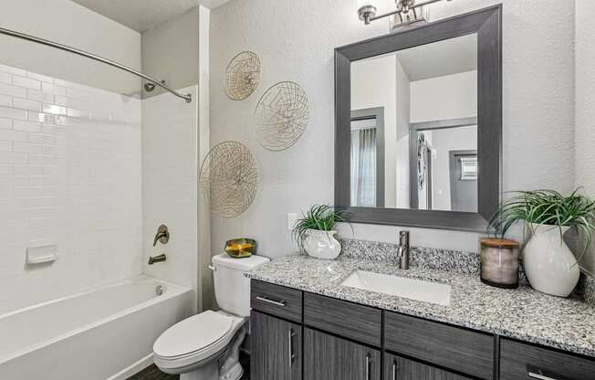 A bathroom with a white toilet, a sink, and a mirror.