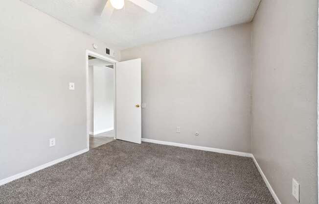 A room with a carpeted floor and a ceiling fan.
