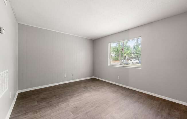 an empty living room with wood floors and a window