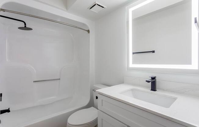 A white bathroom with a toilet, sink, and bathtub.