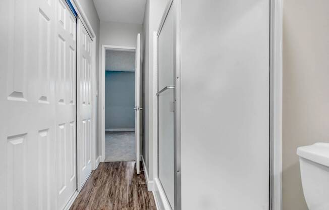 a bathroom with white cabinets and a door to a closet