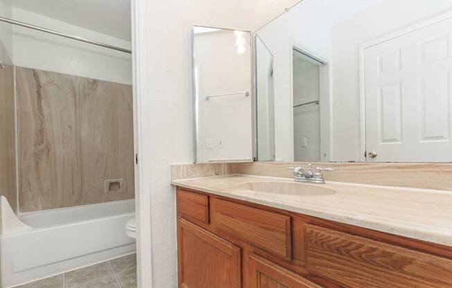 A bathroom with a wooden vanity and a white bathtub.