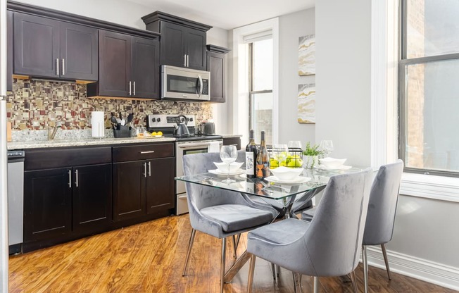 a kitchen with black cabinets and a table and chairs