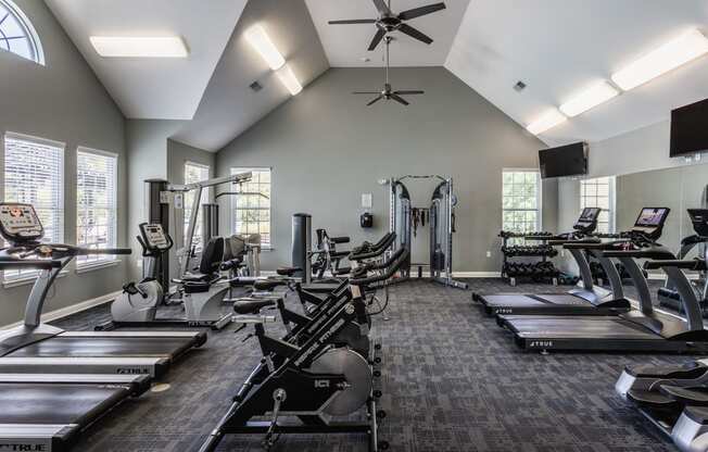 a gym with cardio machines and a ceiling fan