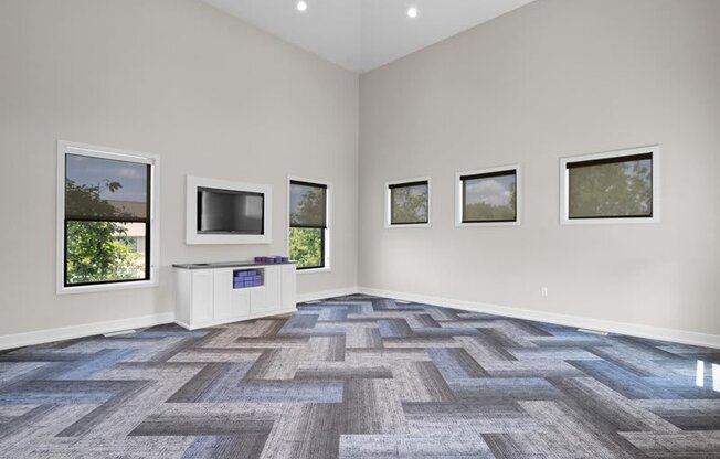 an empty living room with a tv and windows