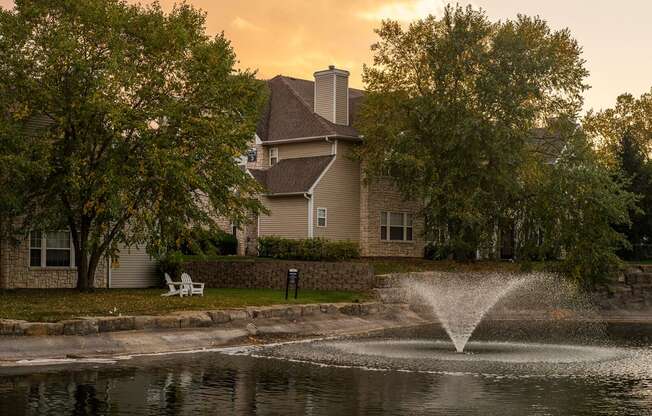 a fountain in a pond with a house in the background