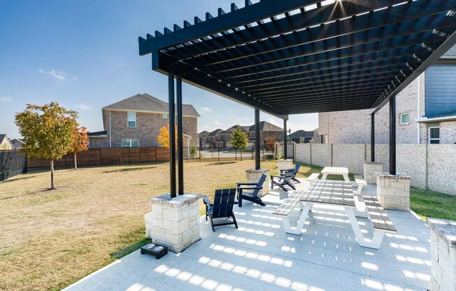 A shaded pergola with communal seating offers a relaxed outdoor setting for gathering, dining, or enjoying time outside within the neighborhood.