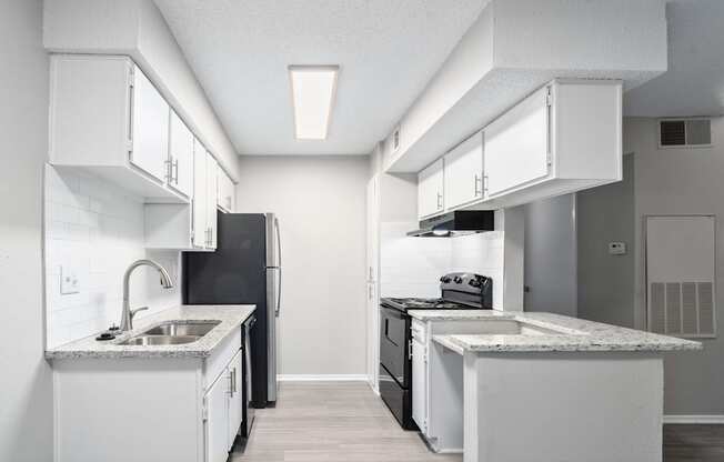 an empty kitchen with white cabinets and a black refrigerator and sink