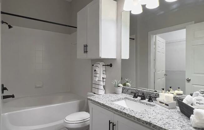 A white bathroom with a tub, toilet and sink.