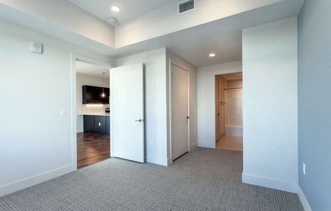 an empty living room with white walls and a door to a bathroom