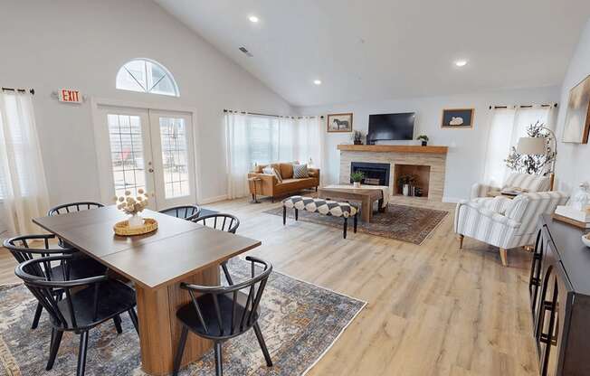 A living room with a fireplace and a dining table with chairs.