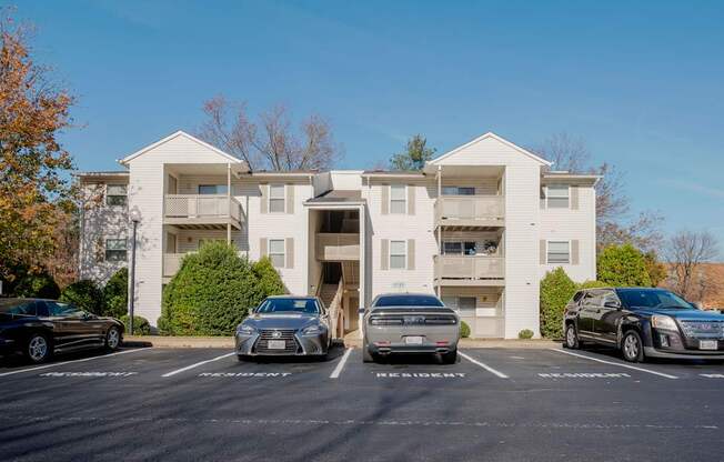 A white apartment building with cars parked in front.