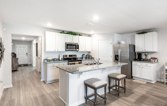 a large kitchen with white cabinets and stainless steel appliances