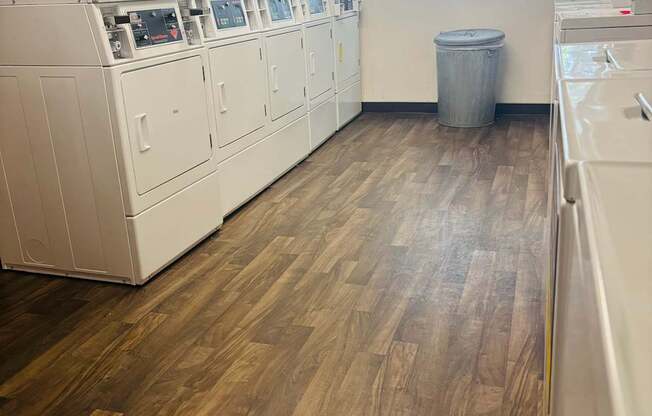 A laundry room with a washer and dryer on the wall and a trash can in the corner.
