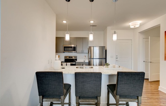 a kitchen with a large island with three chairs in front of it