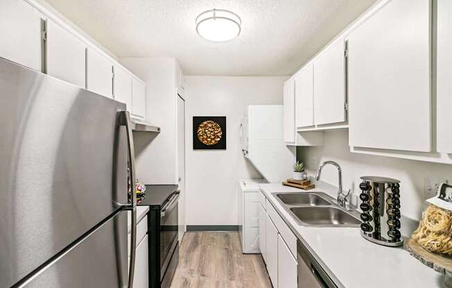 A kitchen with a stainless steel refrigerator and white cabinets.