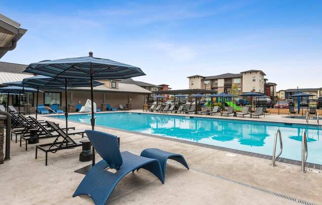 a swimming pool with chairs and umbrellas at the resort on a sunny day