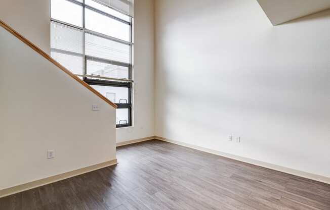 an empty living room with wood flooring and a large window in the loft space