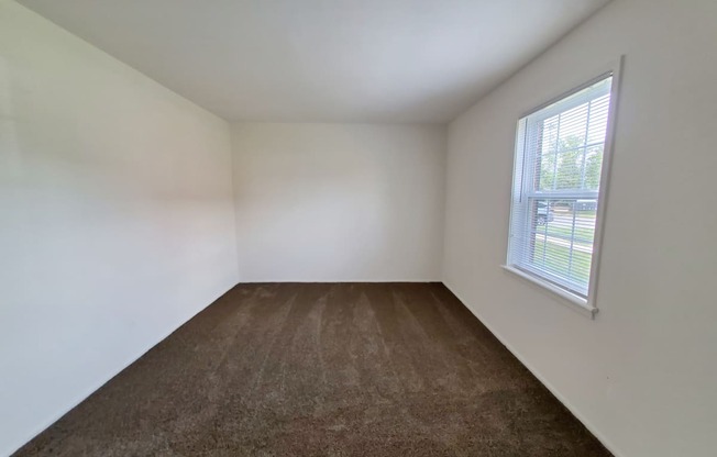 Bedroom in a 1 bedroom apartment with carpet and a window at Carriage House West.