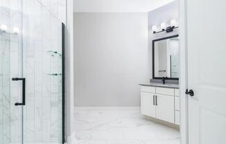 Designer bathrooms with quartz countertops and frameless glass showers.