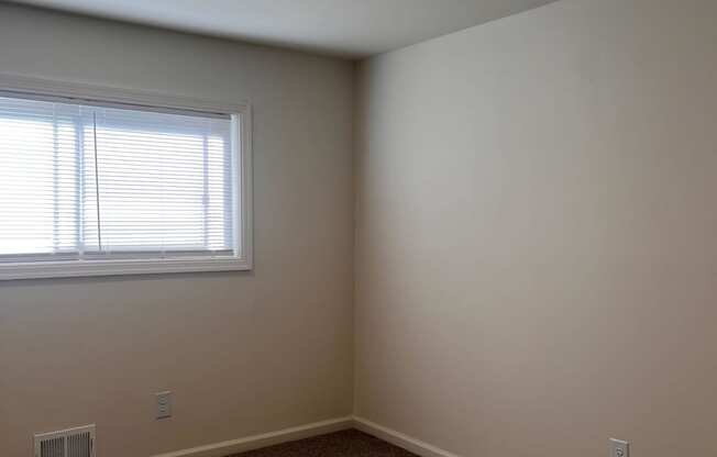 an empty room with a window and a carpet
