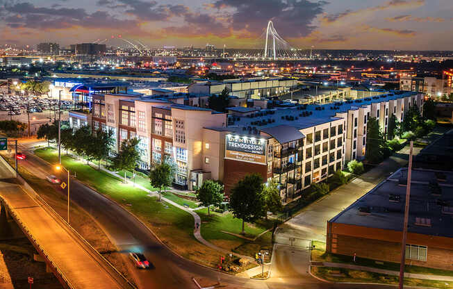 A cityscape at dusk with a bridge in the background.