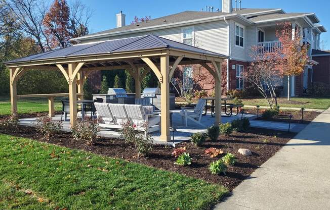 a gazebo with chairs and a patio in front of a house