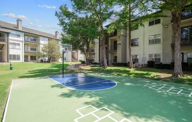 A basketball court and hopscotch area surrounded by apartment buildings at Jefferson Place Apartments in Irving, TX
