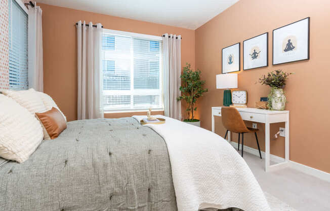 A bedroom with a bed, desk, chair, and pictures on the wall.