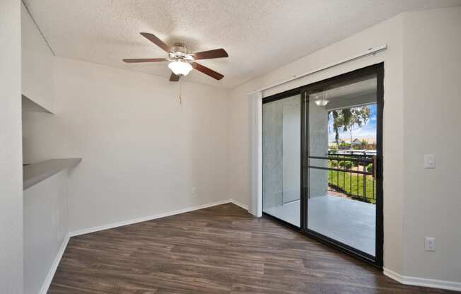 an empty dining area with a sliding glass door and a ceiling fan