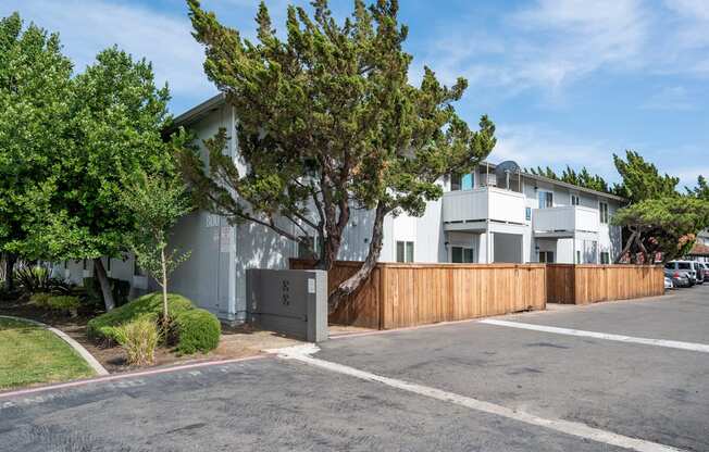 the exterior of an apartment with a wooden fence and a parking lot