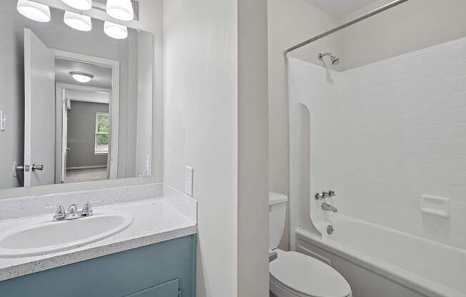 A bathroom with a white tub, toilet, and sink.