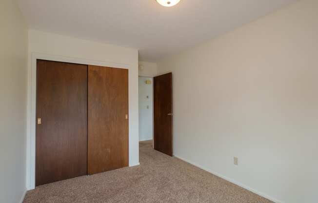 a bedroom with a closet and a door to a hallway. Fargo, ND Country Club Apartments.