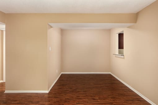 an empty room with a window and hardwood floors