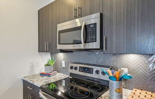 A modern kitchen with a stainless steel oven and microwave above it.