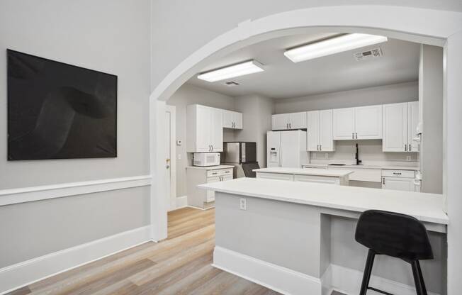 an open kitchen and living room with white cabinets and a white counter top